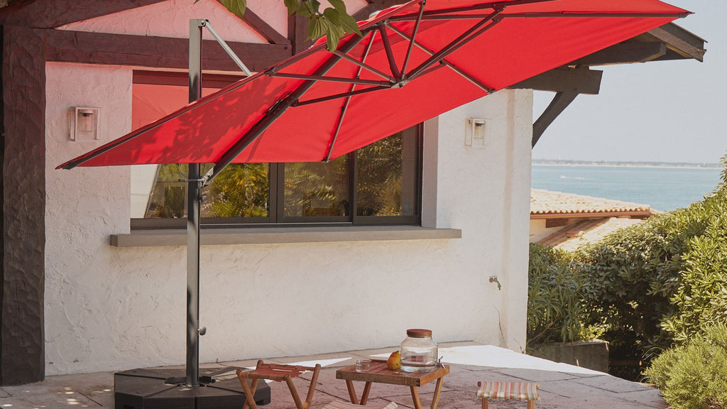 Un parasol déporté à toile rouge dans un jardin 